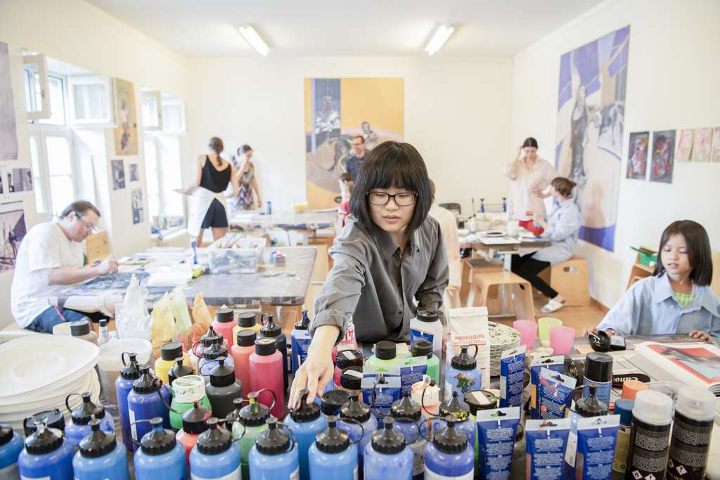 Une femme prend des bacs de couleur dans un studio.