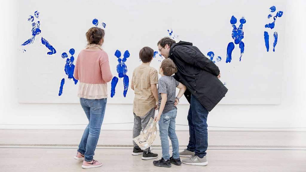 Un groupe de personnes regarde un grand tableau sur le mur.