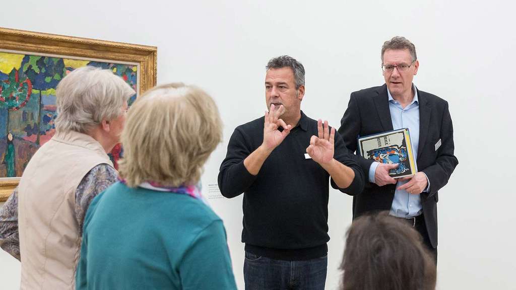 Elderly people get a tour from two art mediators.