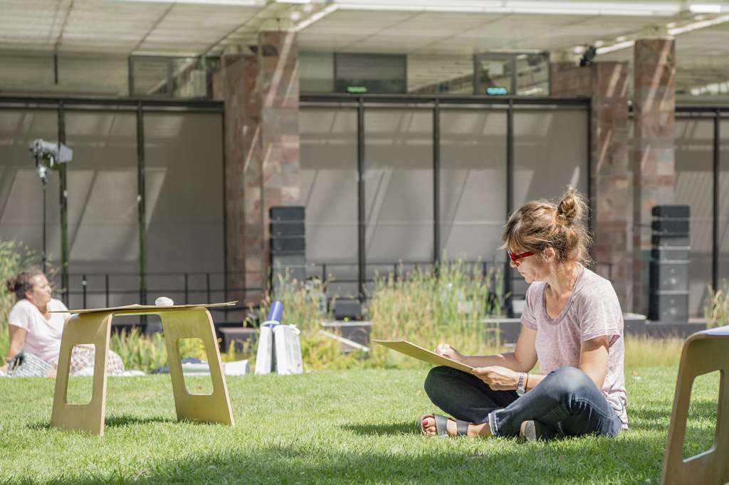 A woman drawing outdoors in front of the museum.