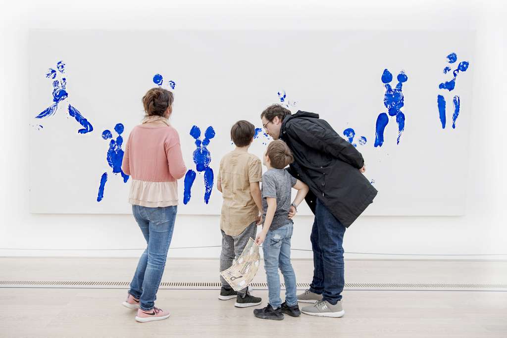 A group of people look at a large painting on the wall