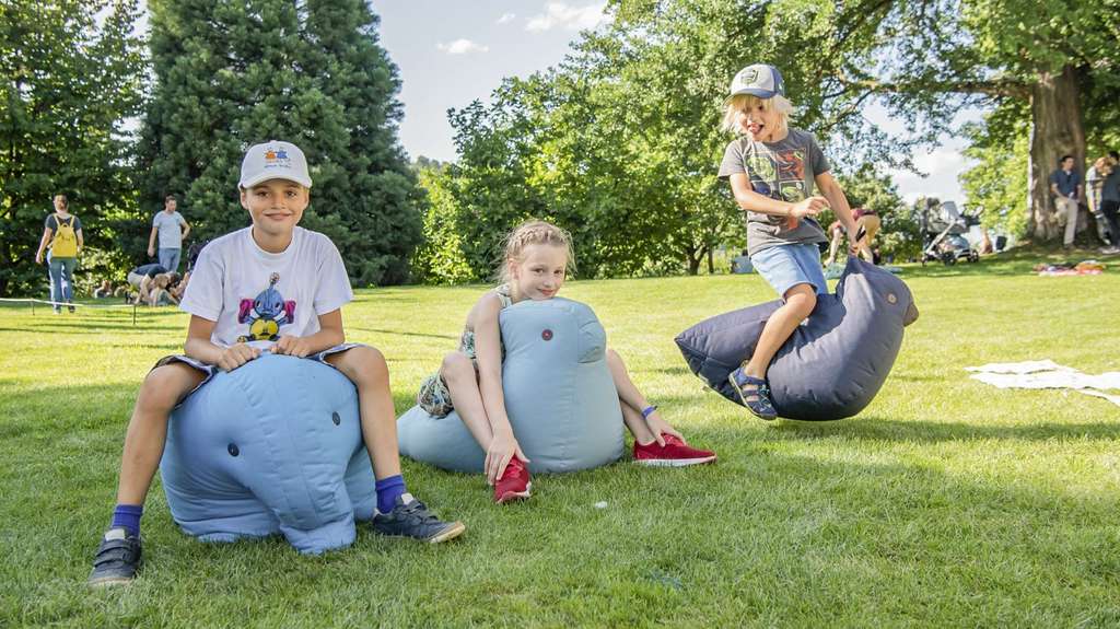 Drei Kinder spielen im Park bei der Fondation Beyeler