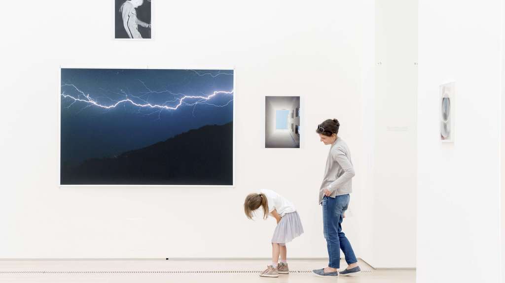 Une femme et une jeune fille devant une collection de photos dans une salle d'exposition.