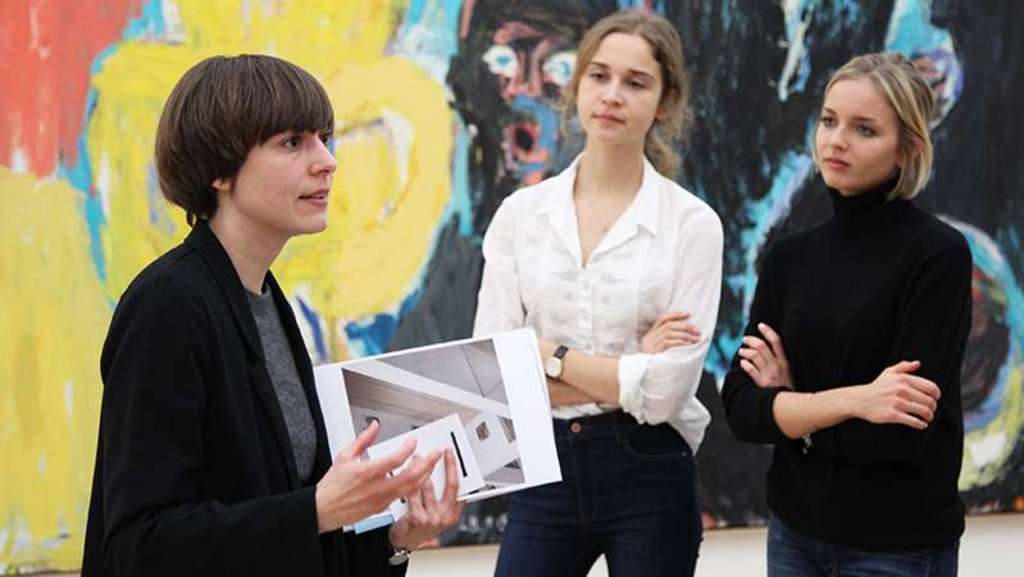Drei Menschen im Gespräch vor einem bunten Kunstwerk.