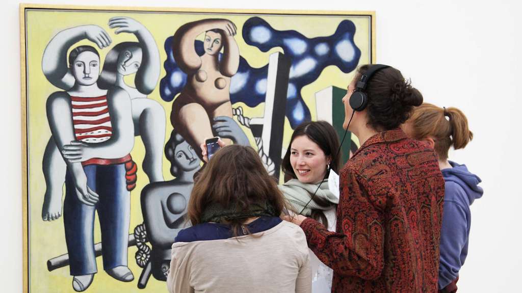 Eine Gruppe von jungen Leuten vor einem modernen Kunstwerk.