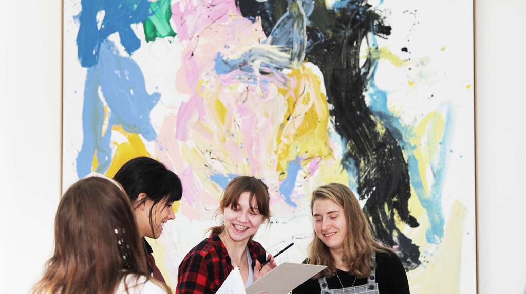 Teenagers in conversation in front of a colourful painting.