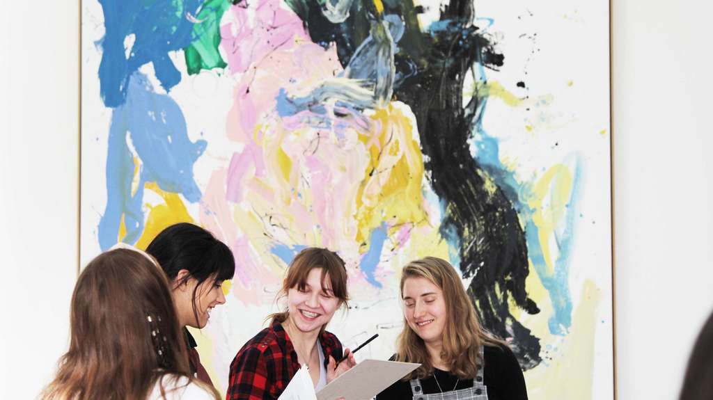Adolescents en conversation devant un tableau coloré.